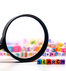 Magnifying glass sits next to colorful blocks spelling out the word search