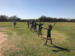 Co ed softball team members stand with their softballs and mitts in the grass