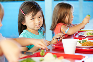 Smiling girl sits with lunch tray