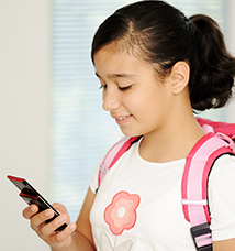 Smiling girl with backpack looks at cell phone