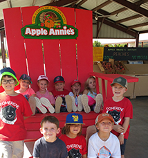 Children sitting on and in front of a big red chair at Apple Annies
