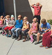 Male staff member and students wear sunglasses and look up at the sun